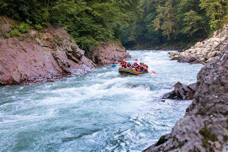 Best Weekend Getaways from Mumbai for 2025 7 group happy people with guide whitewater rafting rowing river